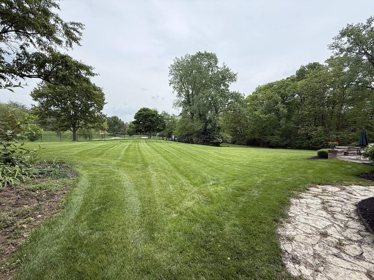Striped back lawn with flagstone patio maintained by Hole in 1 Lawn Care